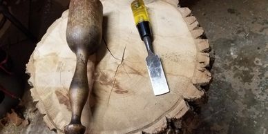 Wood carving tools on a thick tree stump in a workshop.