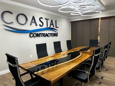 Modern conference room with a unique wooden table and black chairs at Coastal Contractors.