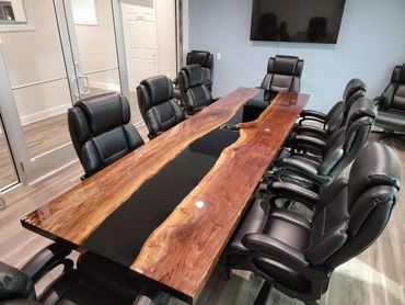 Modern conference room with a unique wooden and black resin table and black leather chairs.