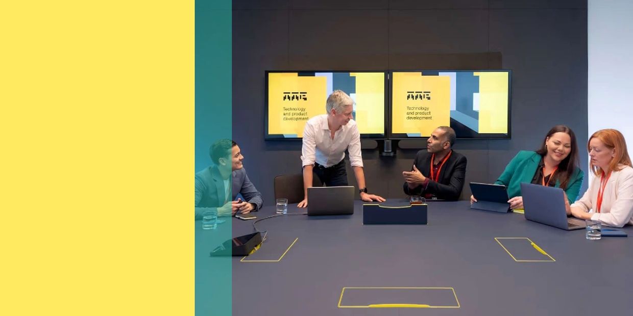 Team collaborating in a modern meeting room with dual screens.