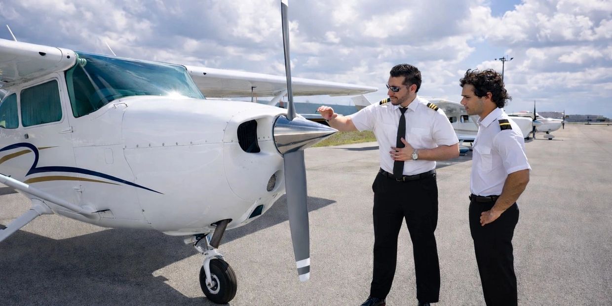 Two pilots inspecting a small propeller airplane on a sunny day.