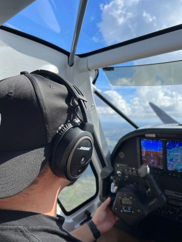 Pilot wearing Bose headphones flying a small aircraft.