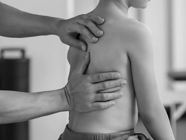 Adult hands examining a child's back, possibly for medical or therapeutic purposes.