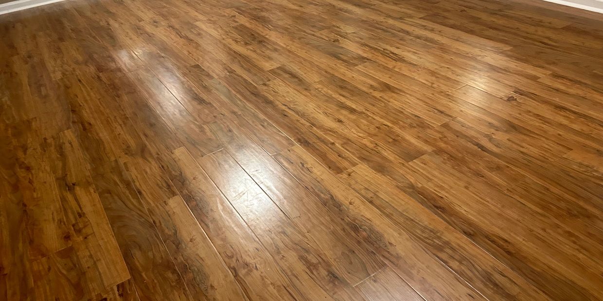 Shiny wooden floor in an empty room with beige walls.