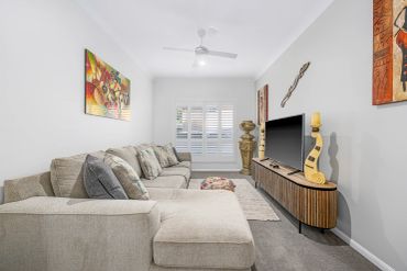 Modern living room with beige sectional sofa and wooden TV stand.