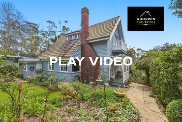 Charming cottage-style house with garden and outdoor seating.