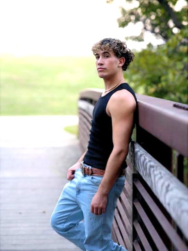 Young man leaning on a bridge rail outdoors.