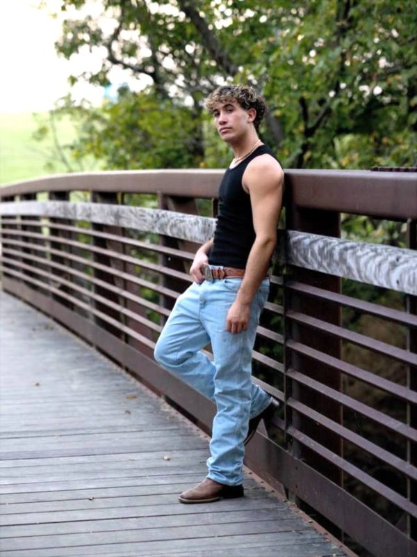Man leaning on a wooden bridge railing.