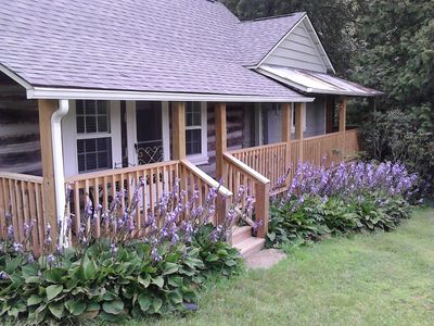 Front of The Old Campbell Farm log cabin and farmhouse accented by hostas in full bloom