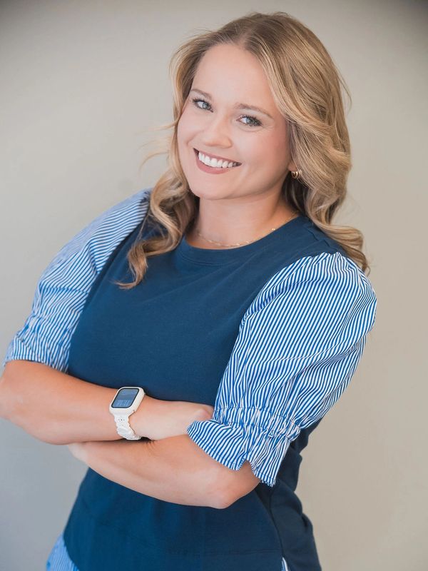 Smiling woman with blonde hair wearing a navy top and white smartwatch.