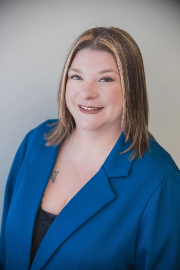 Smiling woman with shoulder-length hair wearing a blue blazer.