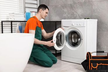 A technician inspecting a washing machine in a modern bathroom.