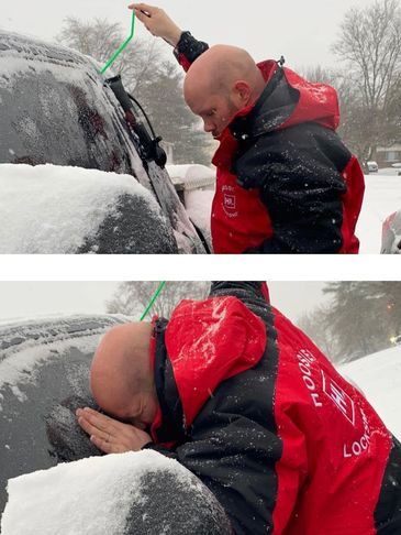 Man in red jacket uses tool to unlock snowy car door.