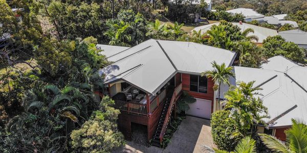 A modern house with a gray roof surrounded by lush greenery.