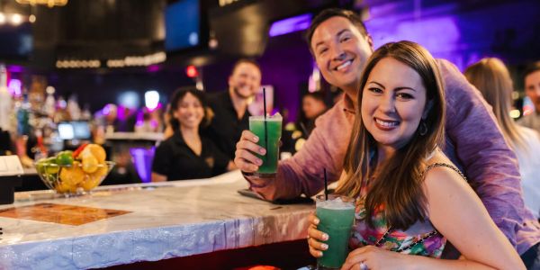 Couple smiling with green drinks at a bar.