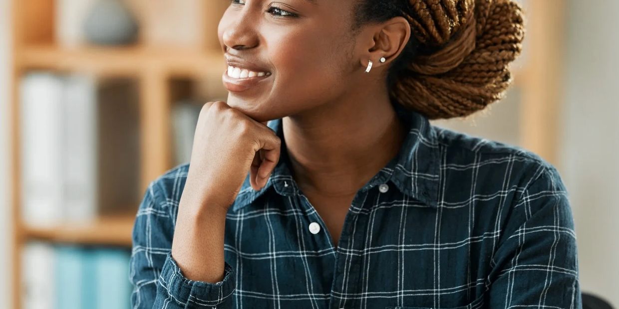 Smiling woman in a checkered shirt looking thoughtfully to the side.