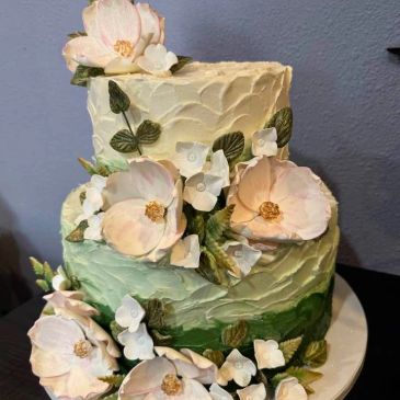 Two-tiered cake with pastel flowers and leaves.