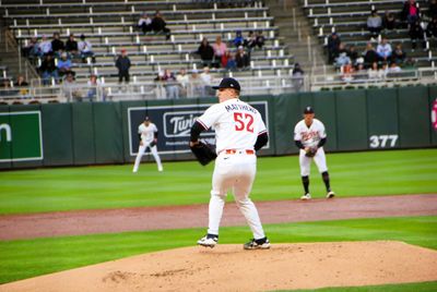 Baseball pitcher in mid-throw on the mound during a game.