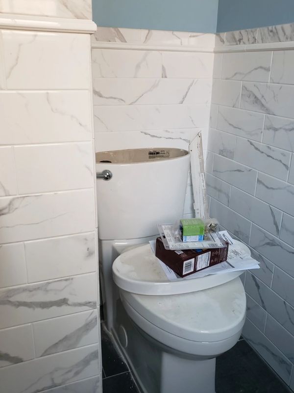 toilet seat with tiles on wall around it