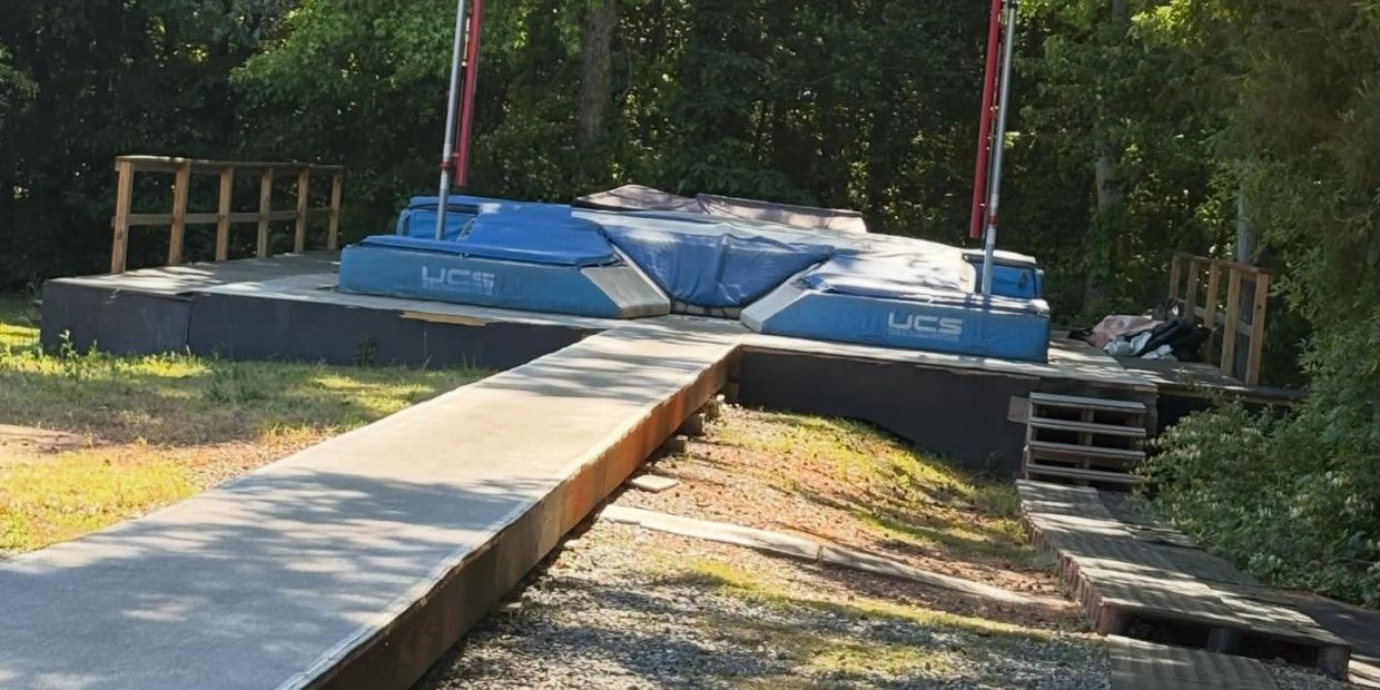 Outdoor pole vault landing area with mats and runway.