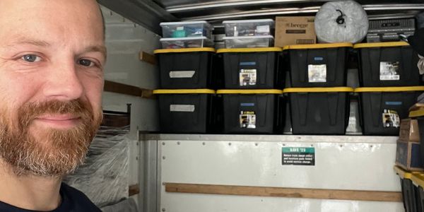 Man taking a selfie in front of stacked storage bins.