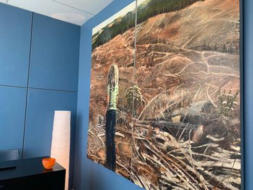 A large painting of a girl in nature hangs on a blue wall in a modern room.