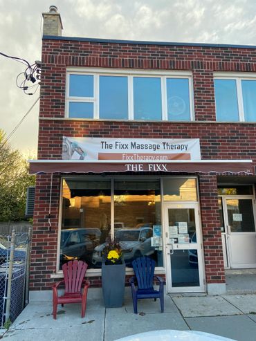 Brick building housing The Fixx Massage Therapy with two chairs outside.