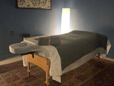 Cozy massage table setup with rolled towel and soft lighting.