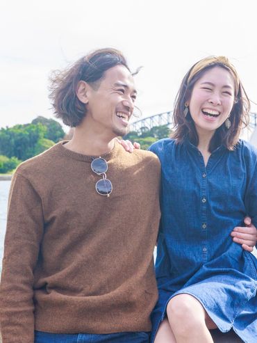 A happy couple laughing together by the water with Sydney Opera House in the background.