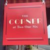 Red signboard with "The Corner at Two One Six" in cream and white text.