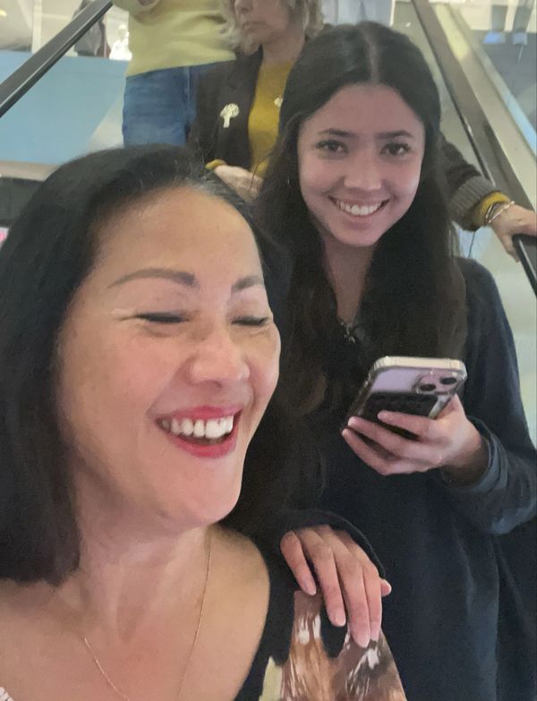 Two women smiling and enjoying a moment on an escalator.