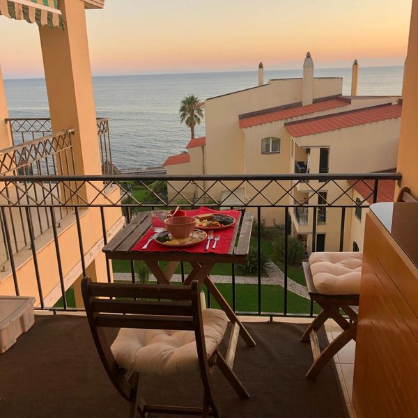 Cozy balcony breakfast overlooking the sea at sunset.