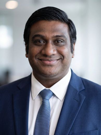 Smiling man in a blue suit and tie, posing for a professional headshot.