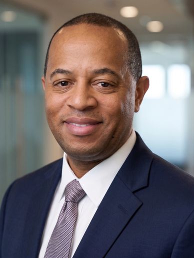 Professional man in a blue suit smiling in an office setting.