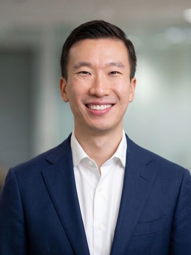 Smiling man in a blue suit and white shirt in an office setting.