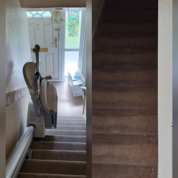Stair lift installed on carpeted stairs next to a front door.