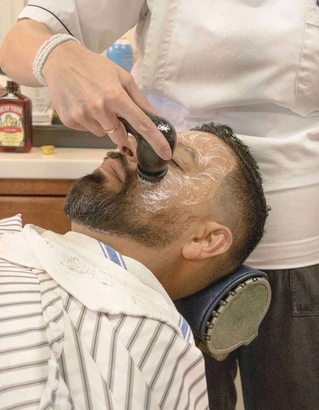 Man receiving a facial treatment at barbershop.