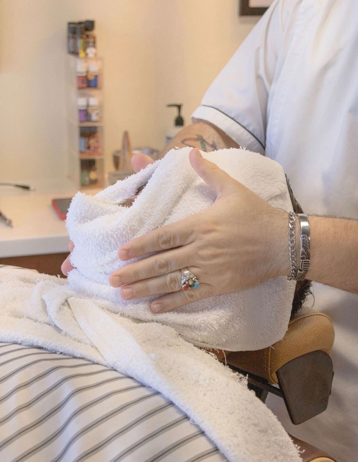 Barber wrapping client's face with a towel.