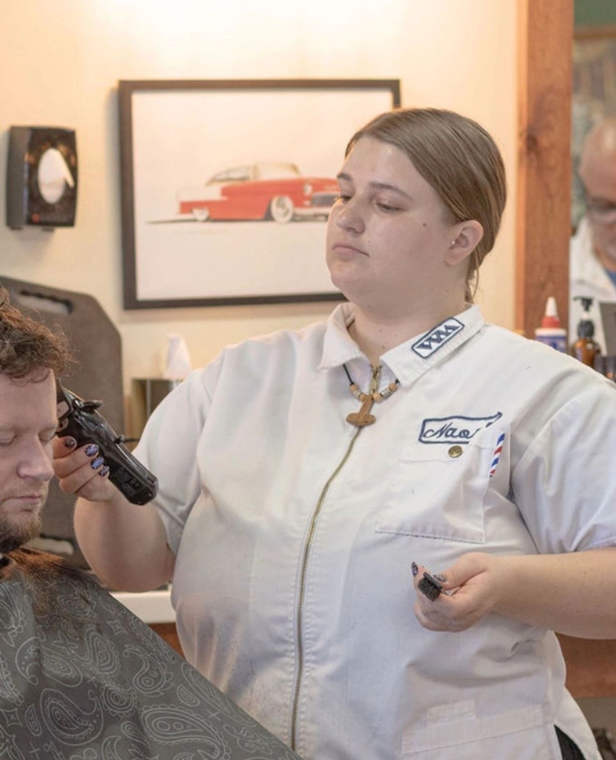 Barber trimming man's hair with clippers.