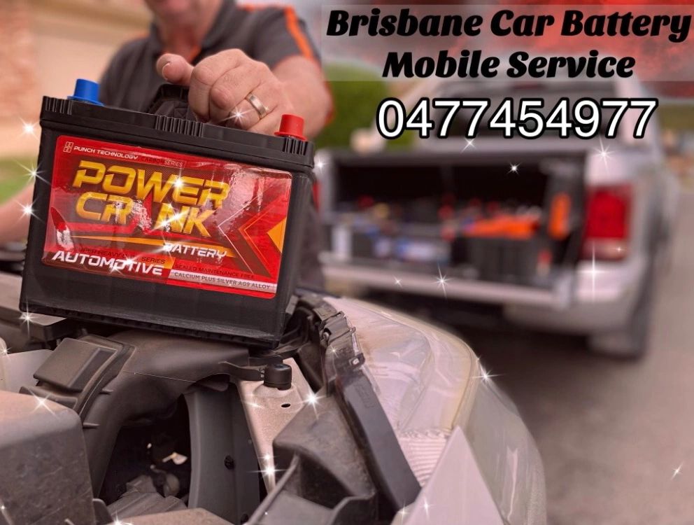 Person holding a car battery with mobile service contact details.