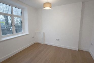 Empty room with wooden floor and large window.