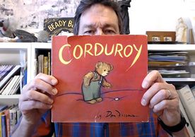 Roy Freeman holds up the book "Corduroy" by his father Don Freeman in front of his face.