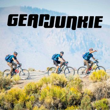 Three cyclists riding mountain bikes on a trail with 'GEARJUNKIE' text above.