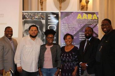 Group of six diverse professionals posing at a conference with banners behind them.