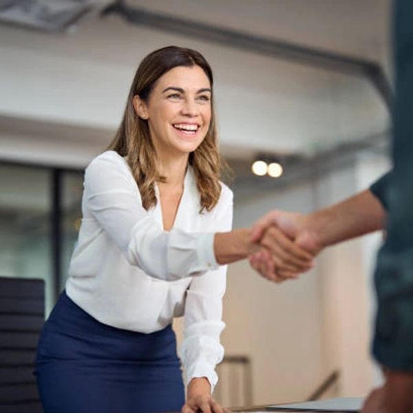 Smiling woman shaking hands in an office setting.