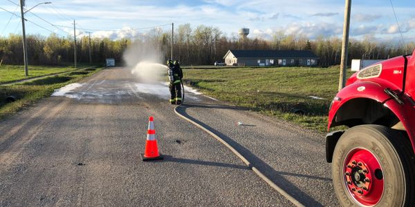 Firefighter training with pumper truck and charged firehose