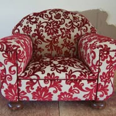 Plush armchair with red floral pattern on white fabric.