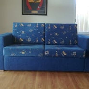 Blue patterned sofa with a wooden floor background.