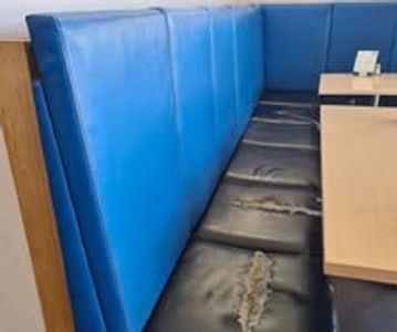 Worn blue and black booth seating with visible tears in a restaurant.