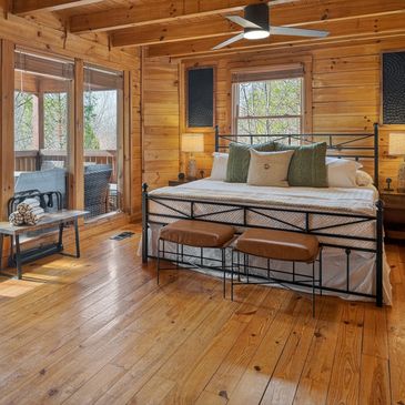 Cozy wooden cabin bedroom with a large bed and outdoor view.